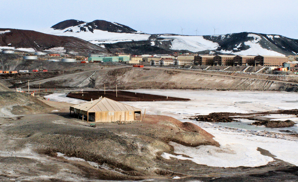 Die Discovery-Hütte auf Ross Island und im Hintergrund die US-amerikanische Basis McMurdo. Von hier aus startete Scott sein Wissenschafts- und Entdeckungsprogramm bis tief in den Kontinent hinein. Bild: Taylor & Francis