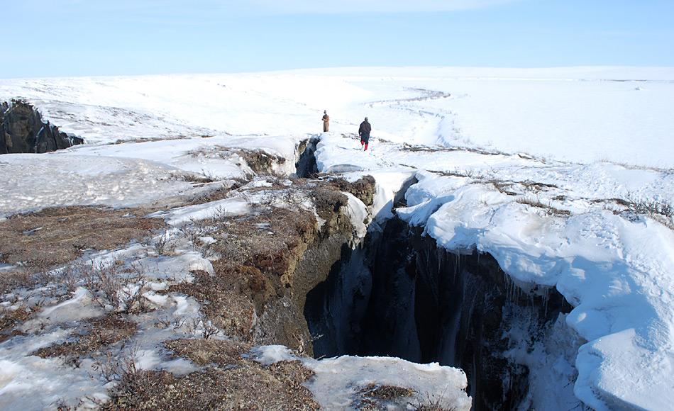 Zwei Forscher gehen neben einem der Erosionsrisse, die sich im Mai 2012 im erodierenden Plateau des Itkillit River gebildet haben. Die Risse waren bis zu 13 Meter tief und bis zu 100 Meter lang. Wenige Tage später stürzte ein 800 Quadratmeter grosses Stück des Plateaus in die Tiefe. Foto: AWI, Daniel Fortier